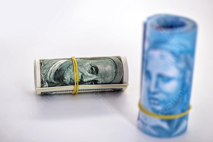 Dólares americanos e reais brasileiros enrolados com elásticos coloridos