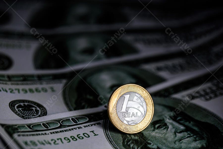 Moeda de 1 Real dourada e prateada sobre notas de dólar americano economia global