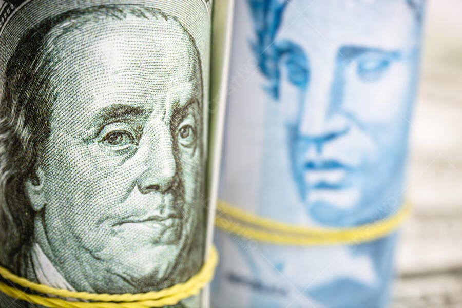 Dólares americanos e Reais brasileiros enrolados com elásticos amarelos