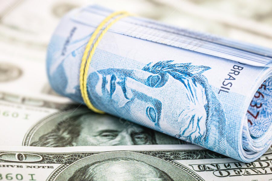 Cédulas de Real enroladas sobre notas de Dólar americano comparando moedas