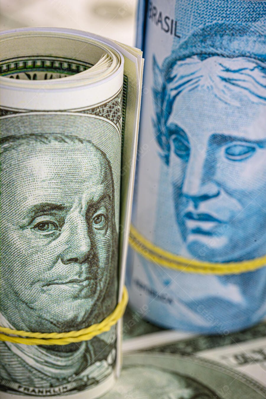 Notas de Dólar e Real enroladas com Franklin e Efígie em close-up financeiro