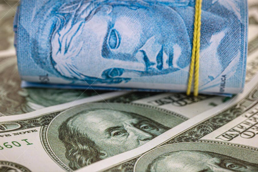 Cédulas de Real enroladas sobre notas de dólar americano finanças e economia