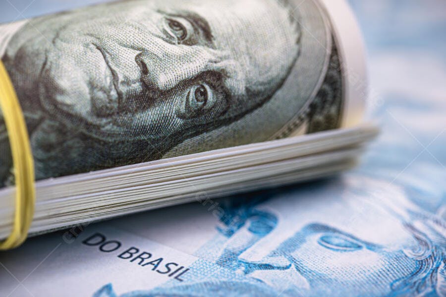 Notas de dólar americano enroladas com elástico sobre reais brasileiros