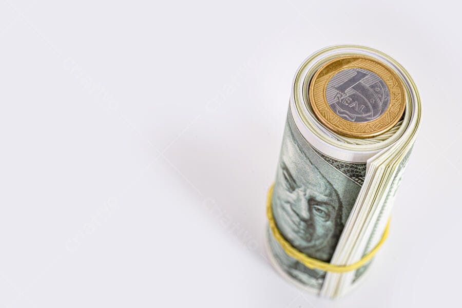 Dinheiro dólar americano enrolado com moeda de 1 real em fundo branco