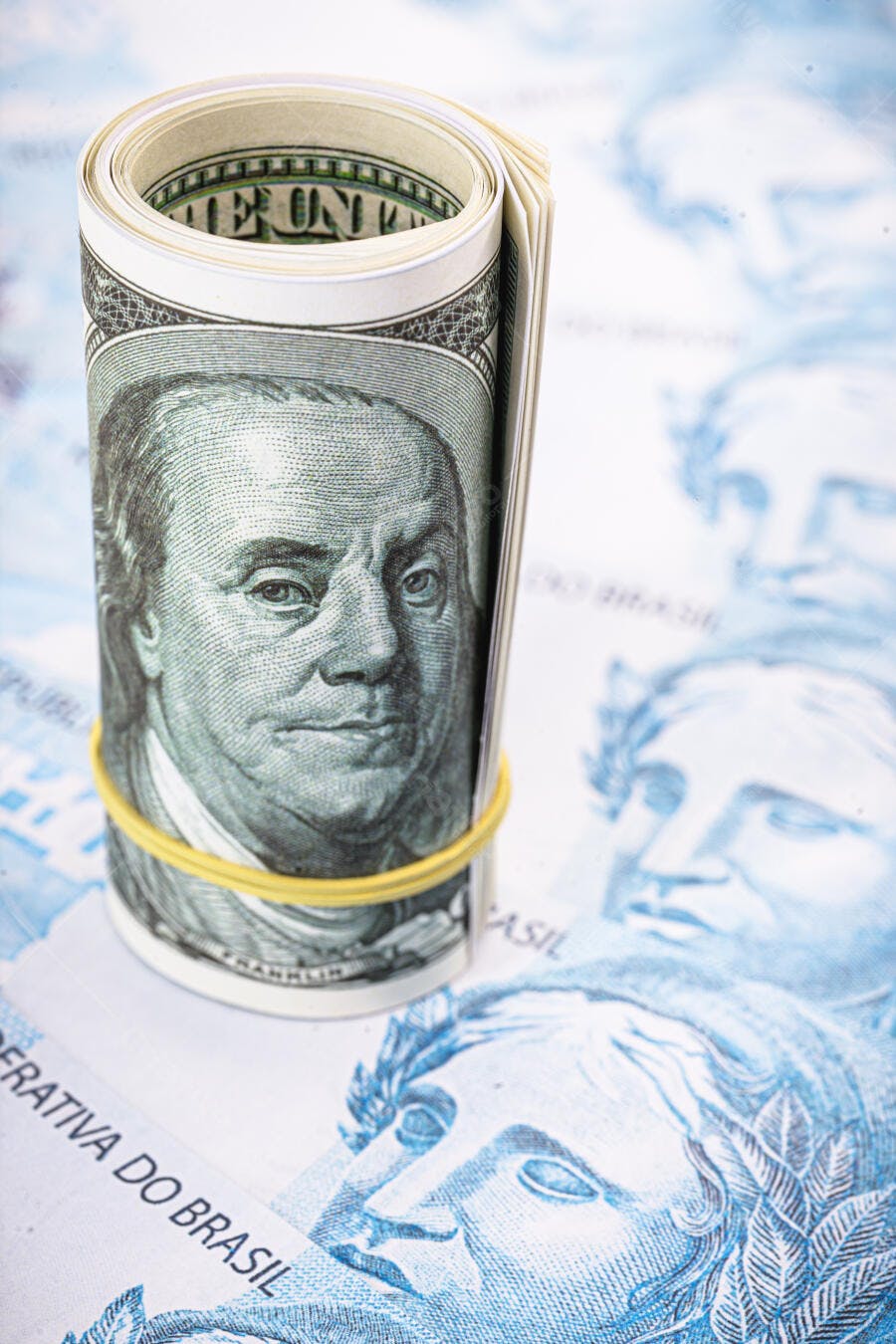 Dólares americanos enrolados sobre notas de Reais brasileiros