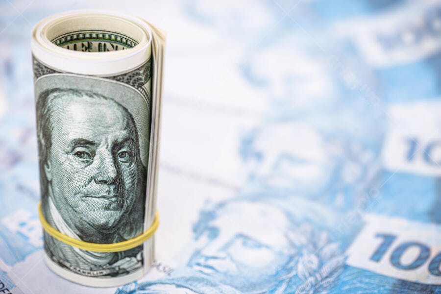 Dólares americanos enrolados em notas de cem reais economia global