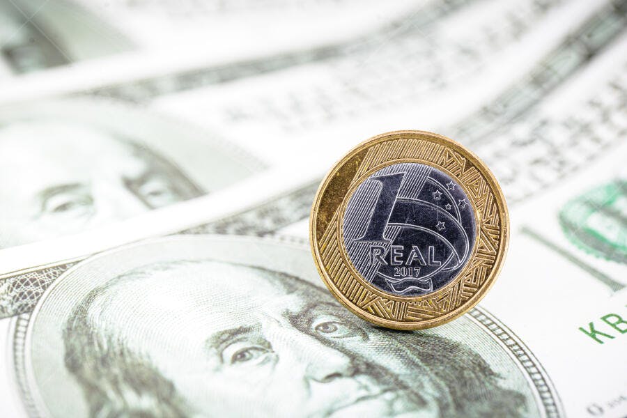 Moeda de um Real brasileiro de 2017 sobre notas de dólar americano