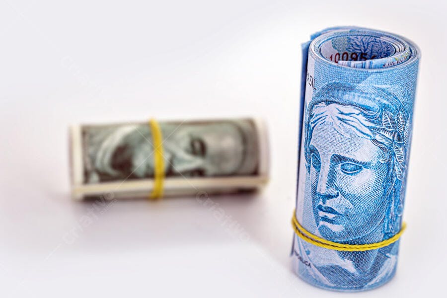 Dinheiro brasileiro Real e dólar americano enrolados em fundo branco