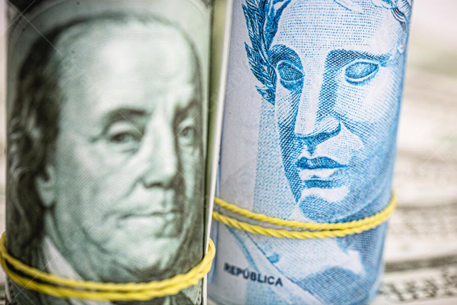 Notas de dólar e real enroladas com elásticos amarelos Franklin e Efígie da República