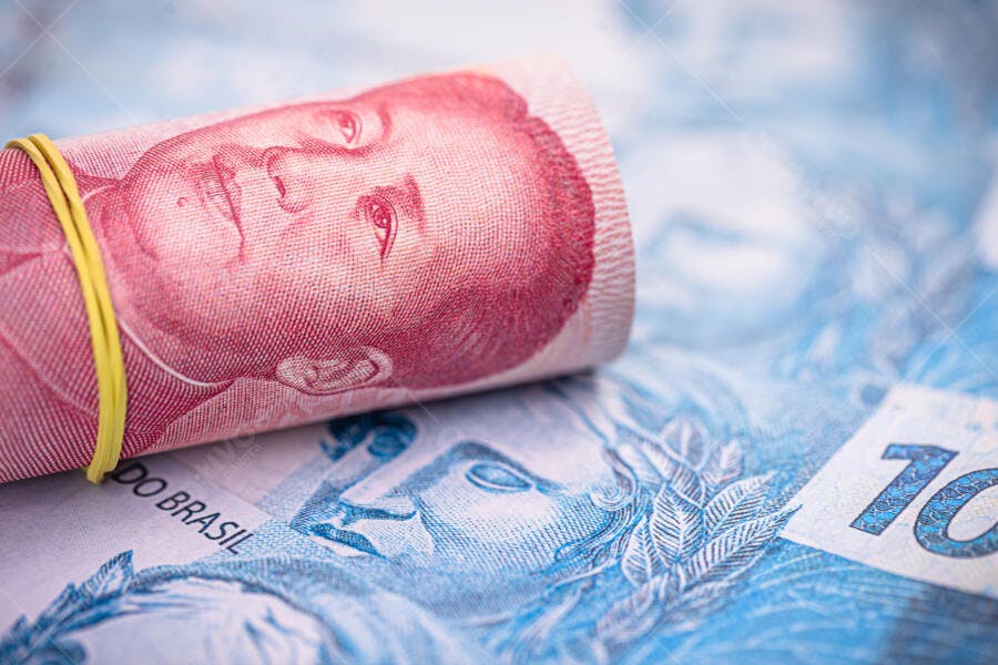 Yuan chinês vermelho enrolado sobre cédula de Real brasileiro economia global