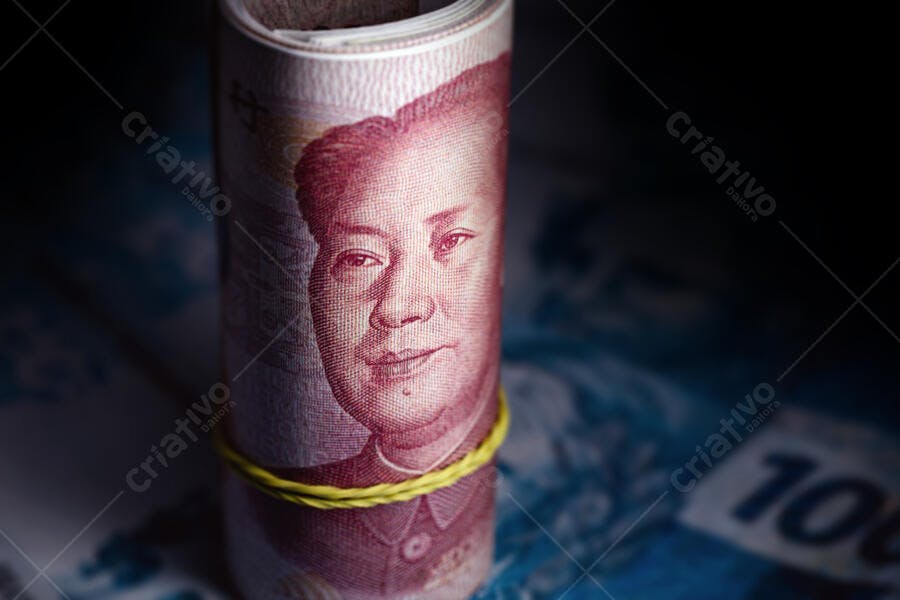 Notas de Yuan chinês enroladas com retrato de Mao Zedong em fundo escuro