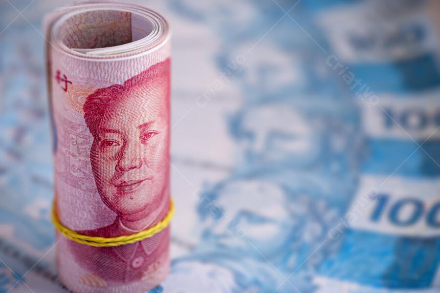 Cédula de 100 Yuan chinesa enrolada com Mao Zedong e elástico amarelo sobre Reais azul