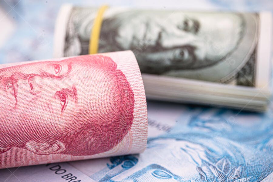 Notas de Yuan chinês e Dólar americano enroladas sobre Reais brasileiros