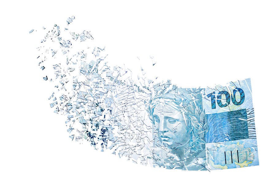 Cédula de 100 Reais brasileira desintegrando em fragmentos azuis sobre branco