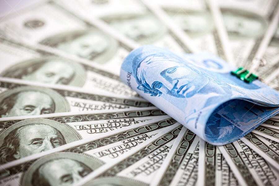 Cédula de real azul sobre notas de dólar americano verde em leque