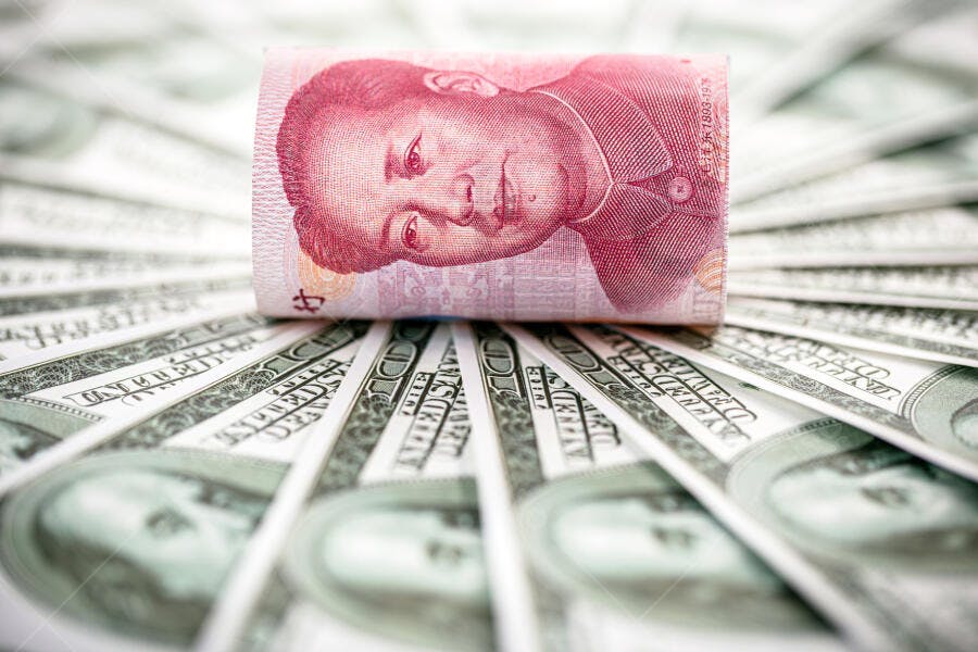Cédula chinesa yuan enrolada sobre notas de cem dólares americanos