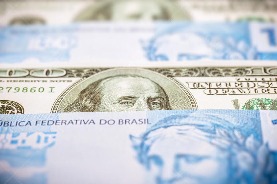 Cédulas de dólar e real em foco representando economia global e câmbio