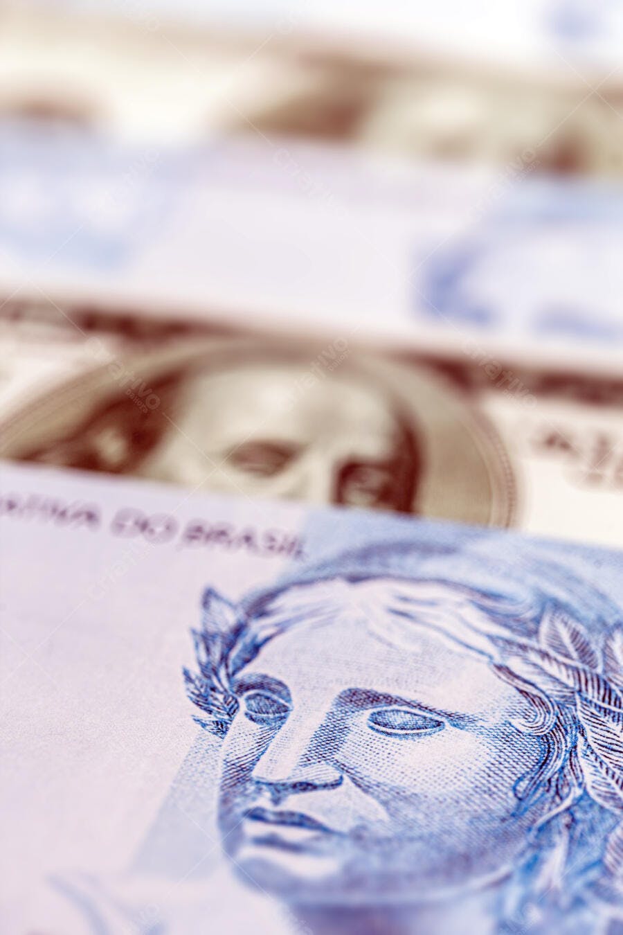 Nota de Real brasileiro em destaque com dólar americano desfocado ao fundo