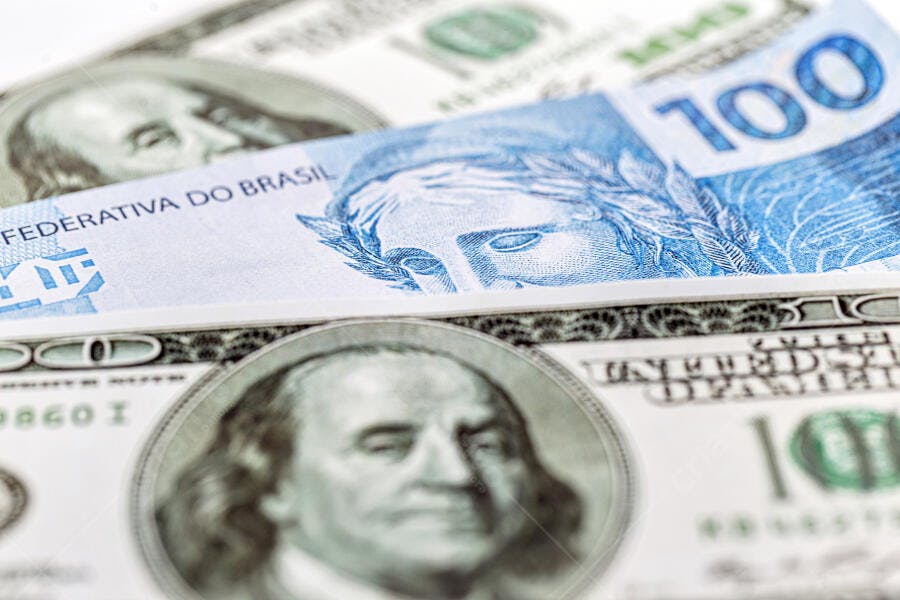 Cédulas de 100 Reais e Dólares americanos em close-up economia e câmbio
