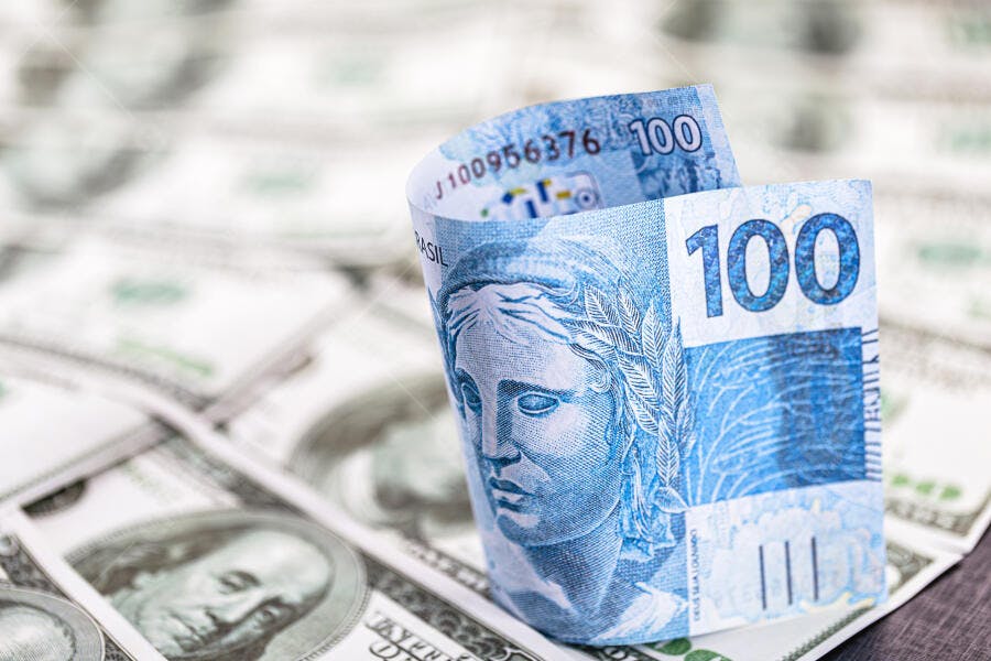 Nota de 100 Reais azul em pé sobre Dólares americanos moeda economia