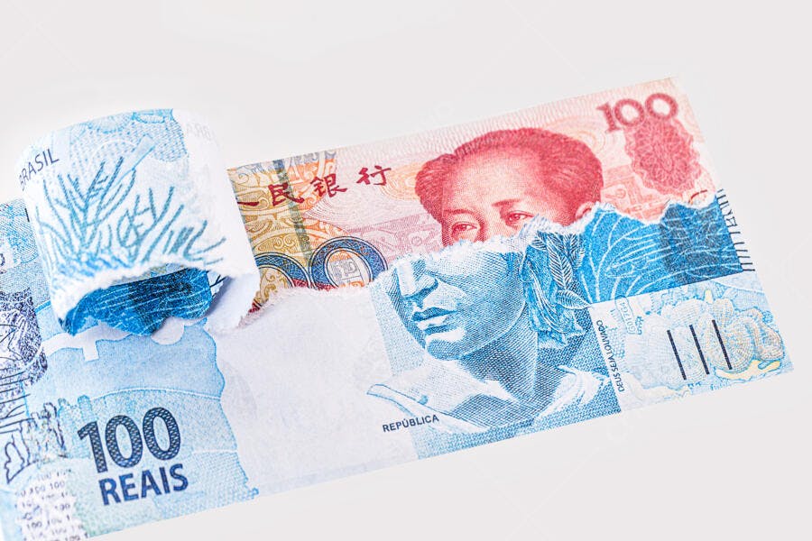 Cédula de 100 reais rasgada sobre yuan chinês finanças globais Brasil China