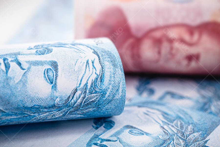 Notas de Real azuis e vermelhas empilhadas em close-up financeiro