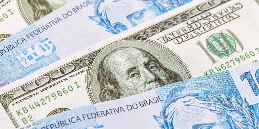 Cédulas de cem dólares e reais brasileiras sobrepostas finanças