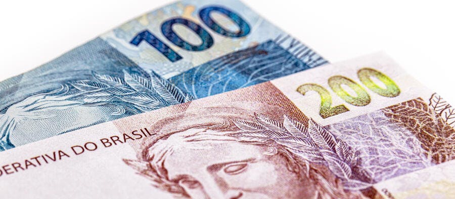 Cédulas de reais 100 e 200 azuis e marrons em closeup de dinheiro brasileiro