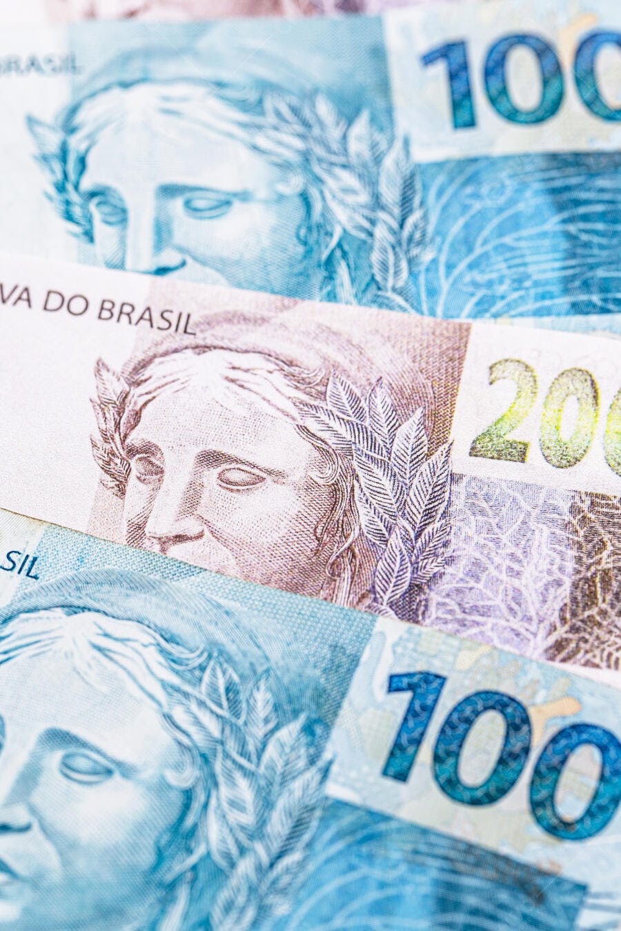 Cédulas de real brasileiro azul e rosa com valores de 100 e 200 reais