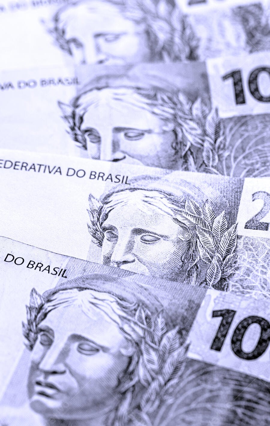Notas de Real Brasileiro empilhadas com efígie em tom azul monocromático