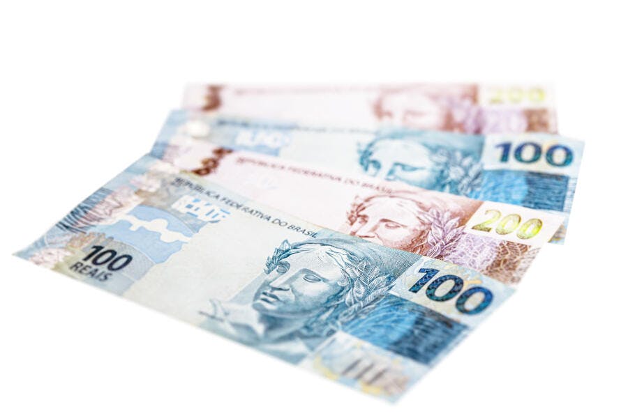 Cédulas de 100 e 200 Reais brasileiras empilhadas em fundo branco