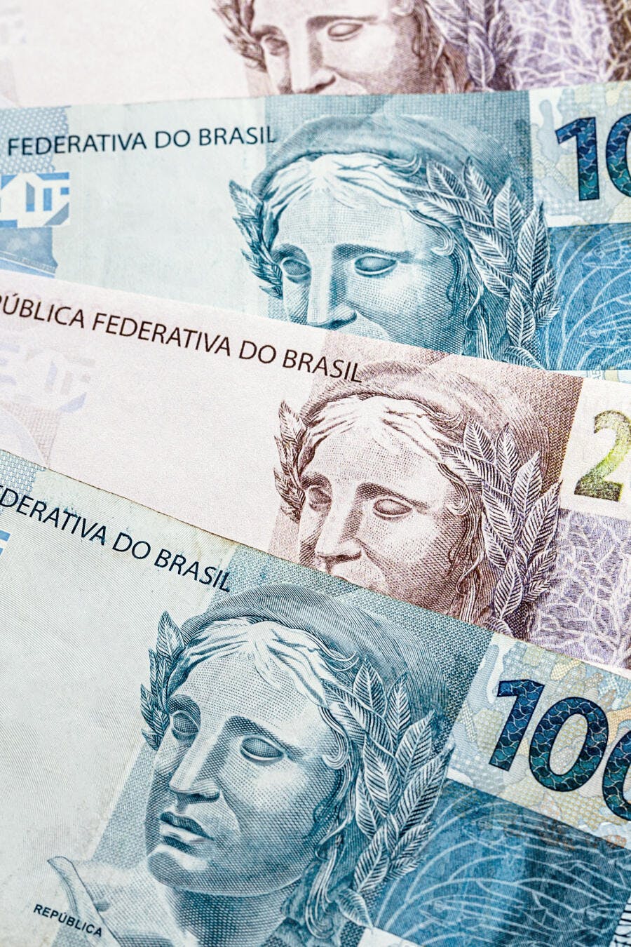 Notas de Real brasileiro empilhadas com detalhes da efígie e valores coloridos