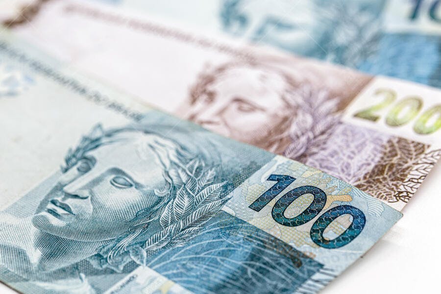 Cédulas de dinheiro Real brasileiro de 100 e 200 Reais empilhadas foco na azul