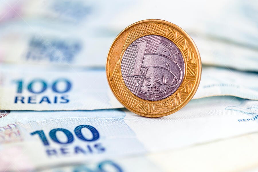 Moeda de 1 Real brasileira sobre notas de 100 Reais macro