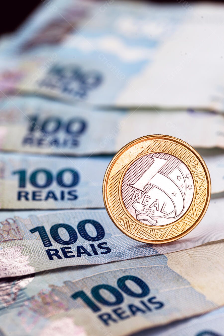 Moeda de 1 real sobre notas de cem reais economia brasileira