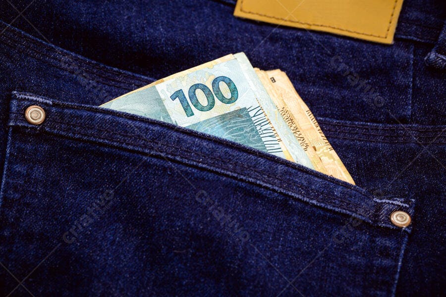 Dinheiro brasileiro cem reais em notas no bolso de calça jeans azul