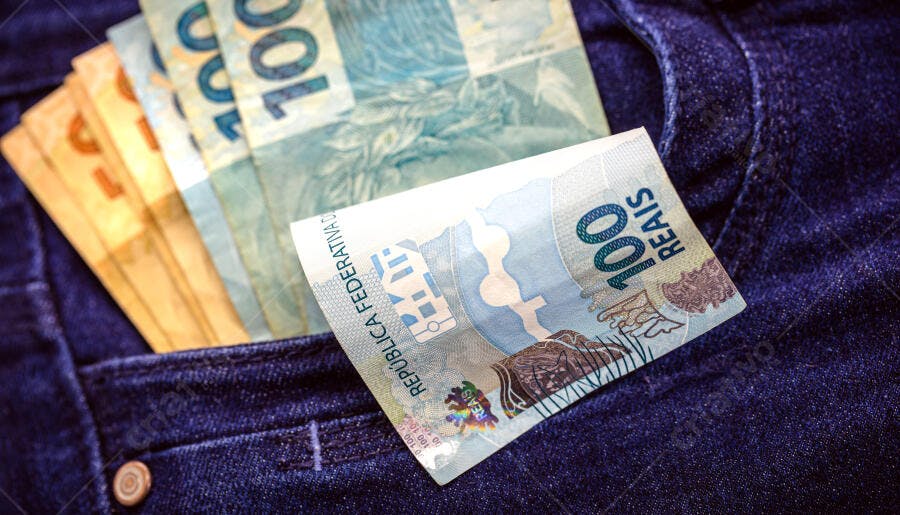 Cédulas de 100 e 50 reais em bolso de calça jeans azul escura