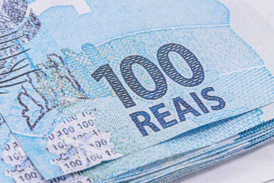 Notas de 100 Reais empilhadas dinheiro brasileiro azul claro