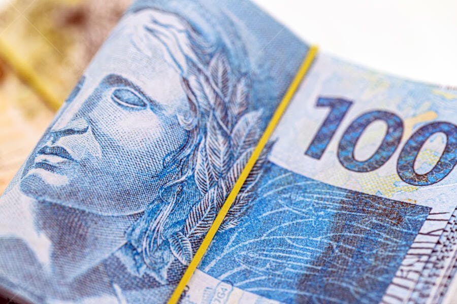 Cédulas de cem reais azuis empilhadas com elástico amarelo dinheiro brasileiro