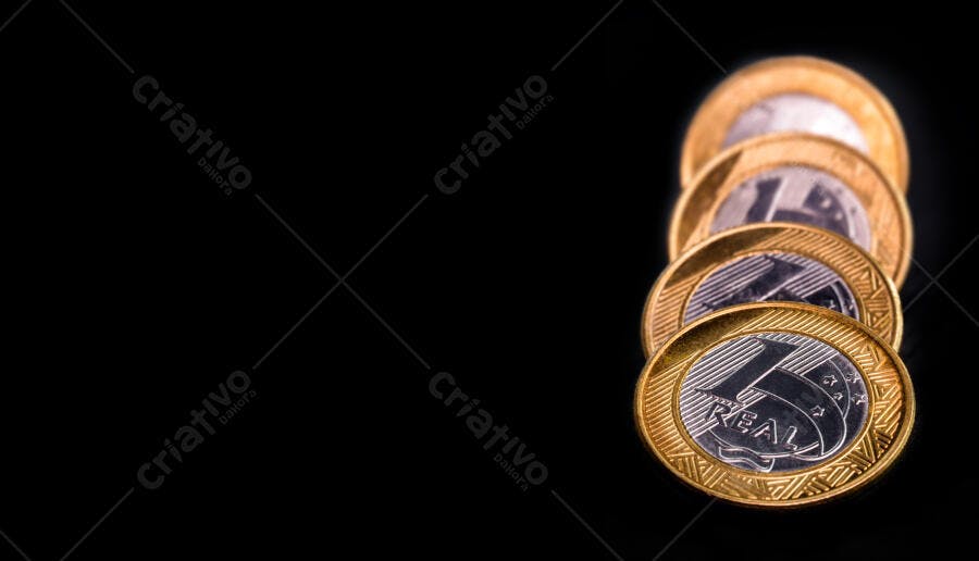 Moedas de Um Real empilhadas em fundo preto simbolizando a economia brasileira