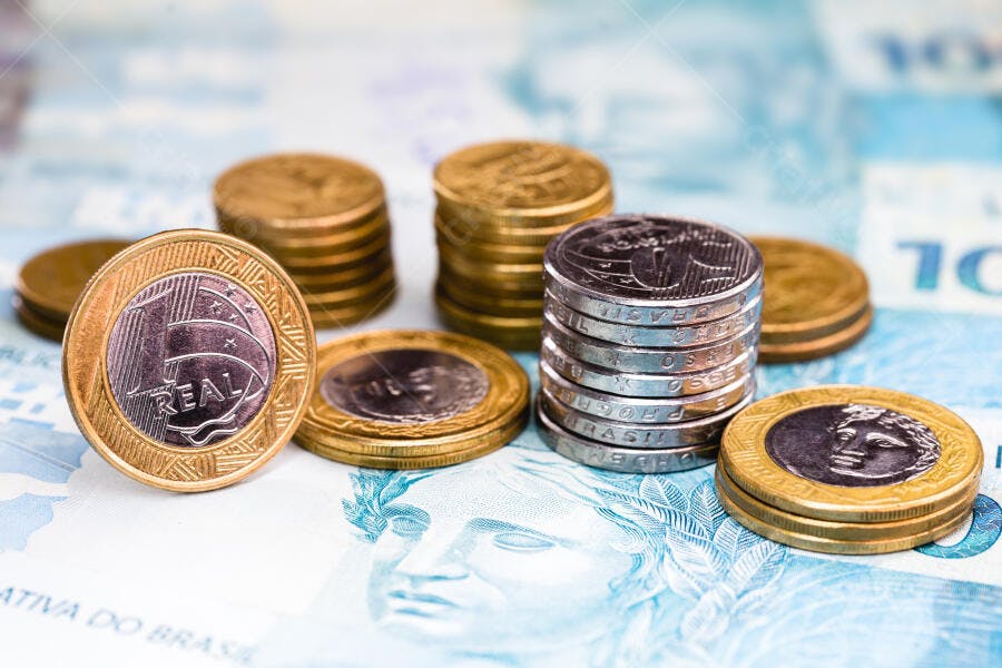 Moedas de Real brasileiro empilhadas sobre cédula de dez Reais