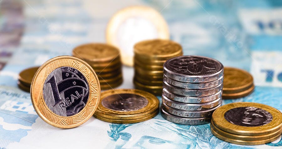 Moedas de Real Brasileiras empilhadas sobre notas de dinheiro finanças e economia