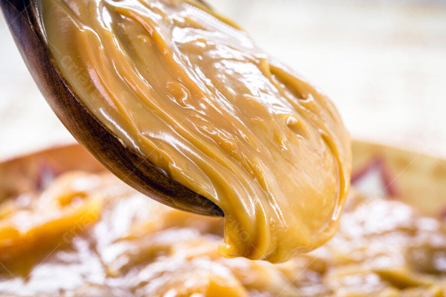 Doce de leite cremoso em colher de madeira dourado e apetitoso