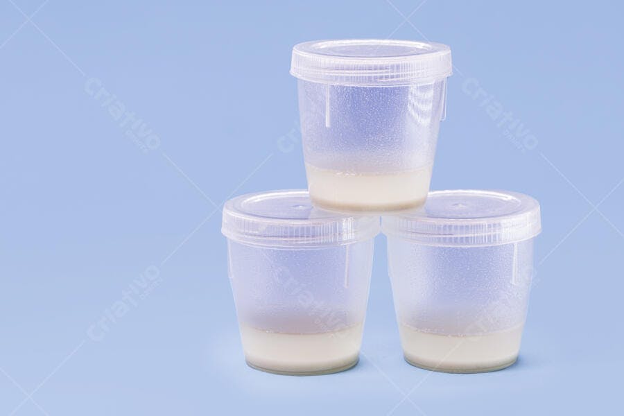 Amostras de leite materno em potes plásticos transparentes fundo azul claro