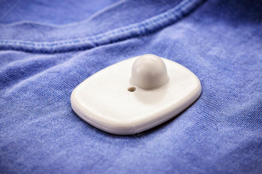 Etiqueta anti furto branca em tecido azul de roupa