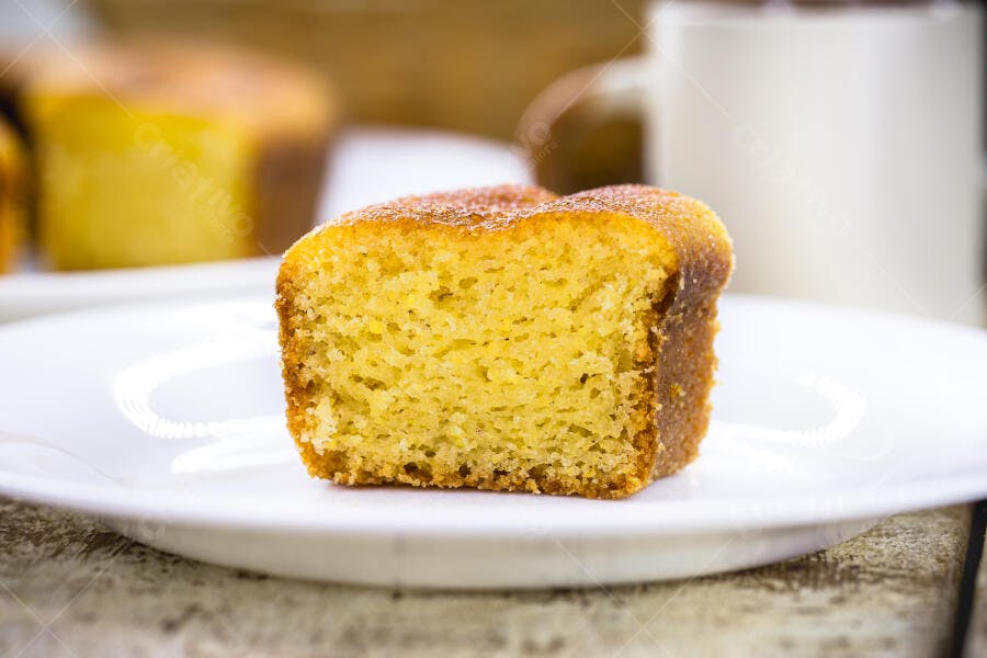 Bolo de fubá fatia individual em prato branco com açúcar por cima