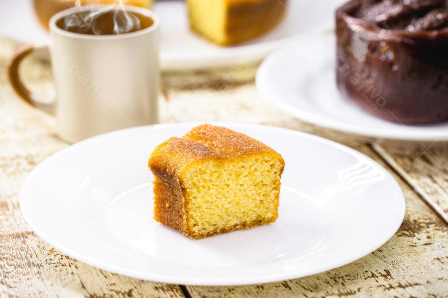Fatia de bolo de fubá em prato branco com café fumegante