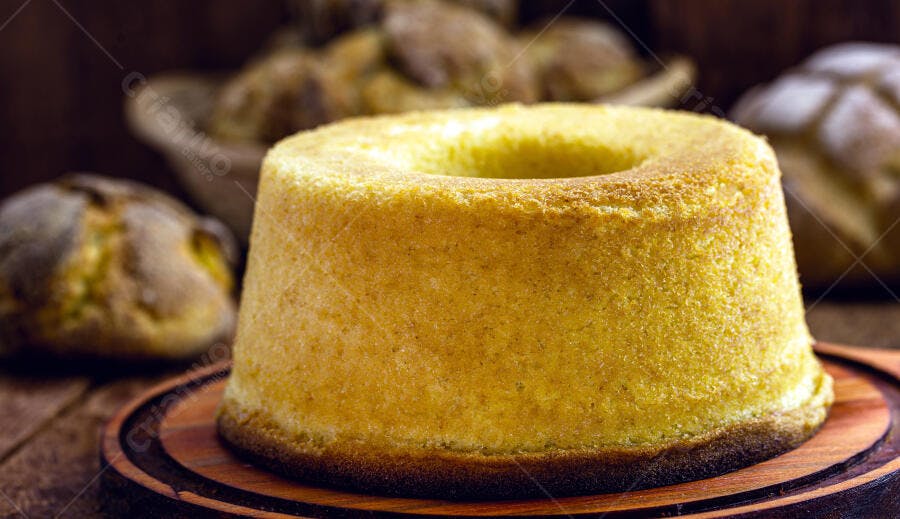 Bolo de fubá amarelo em tábua de madeira rústica com fundo escuro