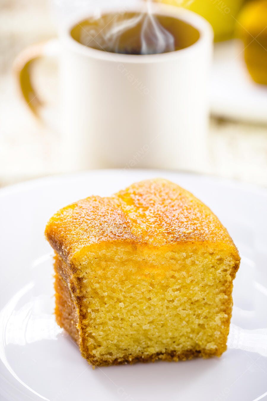 Bolo de fubá amarelo em prato branco com café fumegante