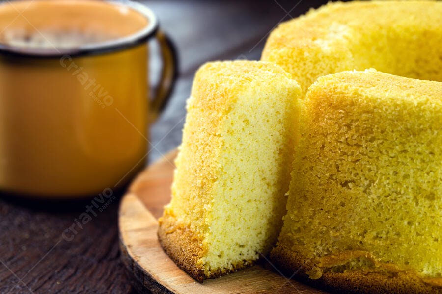 Bolo fatiado amarelo claro em tábua de madeira com caneca amarela desfocada